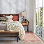 Runner rug in bedroom setting with knitted cream throw on wooden bed and large window to the side