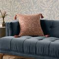 Ellery clay pillow styled on blue tufted couch against wallpaper with floral pattern