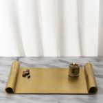 Styled vintage brass tray placed on marble surface with lit candle and chocolate pieces displaying serving use