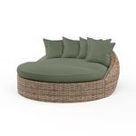 Round outdoor daybed in aged tobacco wicker with plush olive green cushions and multiple pillows