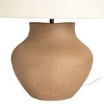 Side view of textured dark sand ceramic lamp base and off-white fabric shade