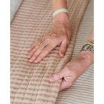 Close-up of hands touching quilted cotton texture of Vancouver Coverlet in amber hue