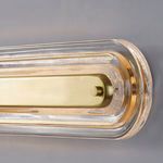 Close-up angle showing textured glass frame and brushed aged brass mounting bar of the wall sconce