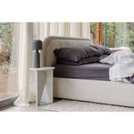 Echo Lamp beside a neutral-toned bed with dark bedding on white marble side table near sheer curtains