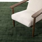 Green rug under beige armchair highlighting scale and room styling detail
