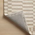 Corner of Bradley rug folded to expose branded cotton canvas backing with Chris Loves Julia x Loloi logo