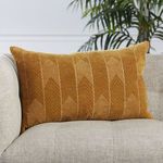 Lumbar pillow positioned upright on beige upholstered sofa armrest with natural light