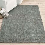 Annello Jute Rug styled in living room next to white sofa on light wood flooring
