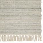Close-up of rug fringe and woven textured pattern in light gray and cream tones
