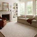 Polly Smoke/Sand rug styled in a bright living room with a beige sofa, leather chair, and fireplace.