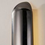 side angle showing warm light glow gently illuminating surrounding wall from black nickel wall sconce