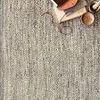 Close-up of chevron waves texture on Omen Grey Rug with stacked leather and wood accessories on top