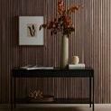Styled room view with Enver rug under dark wooden console table holding books and vases against a slatted wall