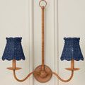 Double-arm wooden wall sconce with two indigo woven chandelier shades mounted on white paneled wall