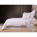 Side view of bed styled with Blake duvet showing relaxed drape and textured white pillow shams against dark wall