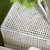 Top-down close-up of glass top showing woven rope texture and decorative plant on outdoor side table