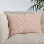 Decorative lumbar pillow positioned on beige sofa armrest near green leafy plant