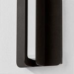 Close-up view highlighting the textured finish and curved edges of the black metal flanges of the Dune sconce