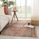 Rug styled in bright living room with sofa, side table, pouf, and book on the floor