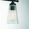 Close-up of single ribbed glass shade with matte black fixture arm and soft light glow