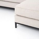 Close-up of sectional sofa chaise base with black iron legs and fabric cushions