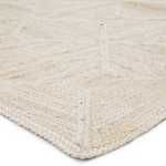 Low angle close-up of rug edge showing braided border and detailed trellis pattern
