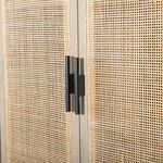 Close-up on black metal hardware handles attached to woven cane doors