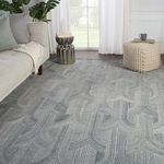 Gray trellis rug styled in a living room setting with natural light, next to a sofa and woven pouf
