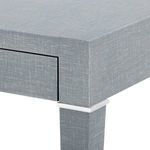 Close-up of desk corner showing linen texture and white metal accent between table top and leg