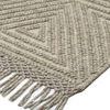 close-up showing rug's textured geometric weave and natural fiber tassels on one corner