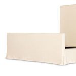 Angled close-up showing footboard slipcover fabric drape and smooth linen texture