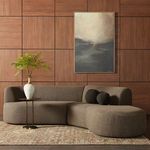 Sectional styled in a room with wooden wall panels, beige area rug, round side table, and two dark brown round pillows
