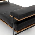 Close-up focusing on armrest cushion with oak trim and matte black steel support post