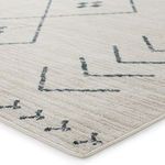 Close-up of woven cream and dark slate tribal rug corner showing texture and edge binding