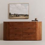 Dresser styled in a room setting under landscape painting with decorative books and marble sphere on top