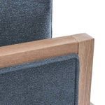 Close-up of the textured blue fabric upholstery and smooth natural wood finish on the armrest