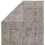 Gray oriental rug flipped to show backside with muted pattern and tight weave