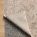 Louisa oatmeal rug corner lifted to reveal non-slip dark gray rug pad underneath