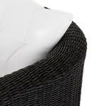 Detail of curved wicker armrest and edge of tufted white seat cushion