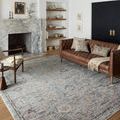 Rug placed in a modern living room with brown leather sofa, armchair, fireplace, and built-in shelves