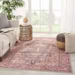 Rug styled in a natural light room next to a beige sofa, rattan side table, and poufs