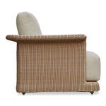 Side angle focused on Meredith chair’s thick seat cushion and wicker armrest curve