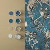 Side-by-side swatches of Perrow Wallpaper next to paint samples in blues and neutrals
