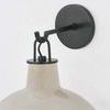 Close-up of black metal wall mount and hardware connecting to beige ceramic shade of Pottersville Wall Sconce