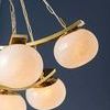 Side view focusing on four lit seeded glass shades on gold curved bands against dark background