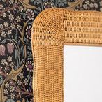 Close-up of upper left corner showing mirror against floral wallpaper backdrop with natural rattan detail