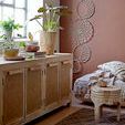 Cozy room corner showing carved stool beside woven blanket and dreamcatchers on terracotta wall