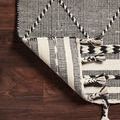 Corner of Sawyer Black Rug lifted to reveal the reversible underside with black and white stripes