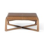 Back view of ottoman highlighting wood frame and side profile of padded leather top