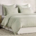 Angled view of bed with duvet and shams showing texture and relaxed drape on side of bed